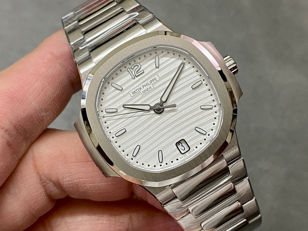 Wristwatch dial close-up with baton markers and date window at 3, silver background