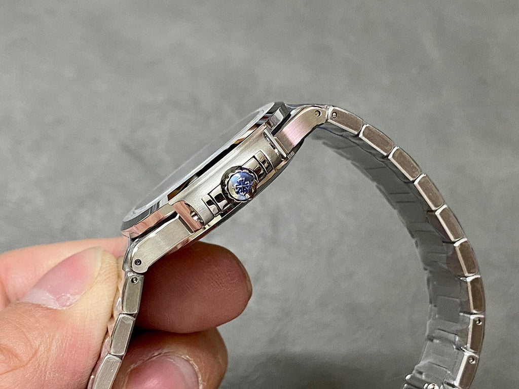 Patek Philippe wristwatch case with crown and blue gem set on bezel.