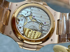 Open watch caseback showing gold balance bridge and mechanical gears, gold-tone