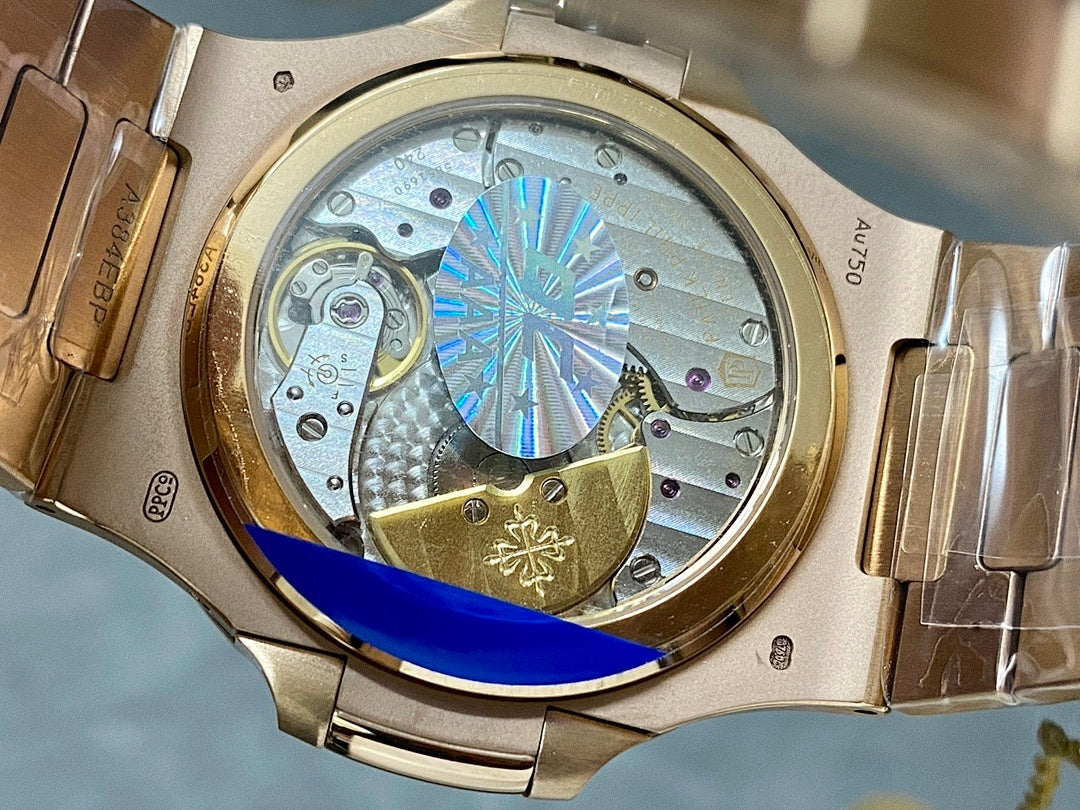 Open caseback with visible gears and blue starburst wheel, gold-tone wristwatch