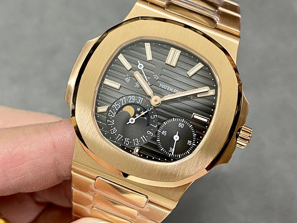 Gold-tone Patek Philippe wristwatch with black dial and gold bezel, held in hand