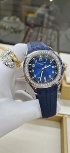Patek Philippe watch with blue dial and bezel stones, blue rubber strap.