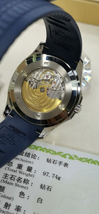 Patek Philippe watch open caseback with gold-toned movement and blue rubber strap.