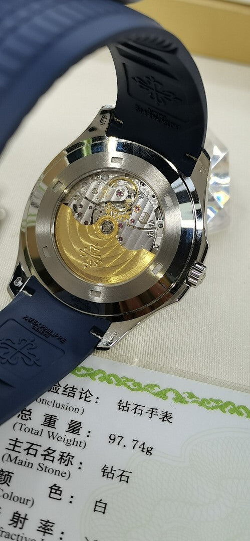 Patek Philippe watch open caseback with gold-toned movement and blue rubber strap.