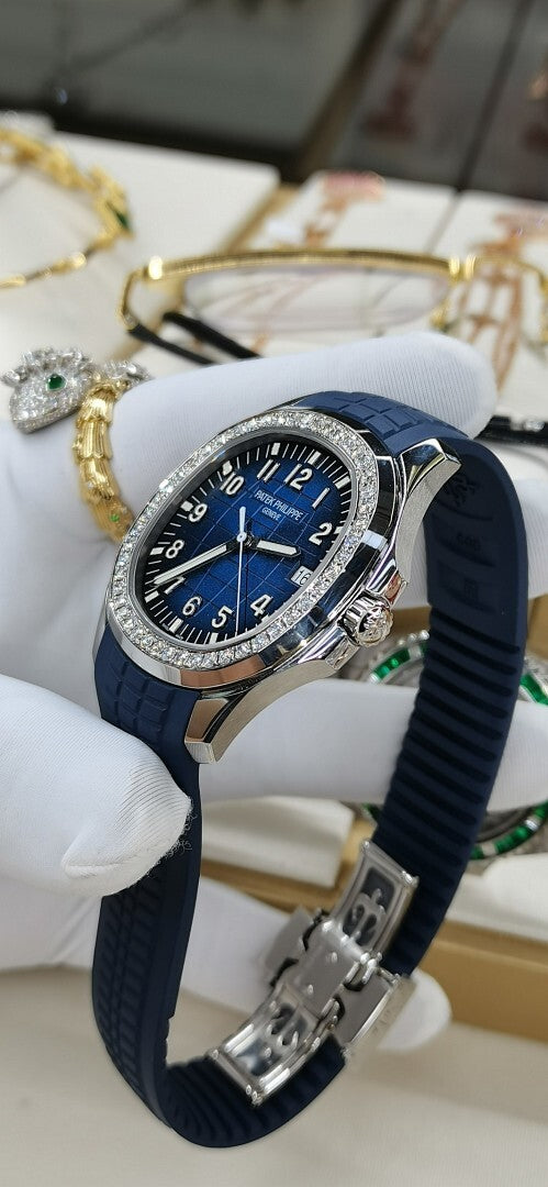 Patek Philippe watch on blue strap with blue dial and jeweled bezel, clasp visible.