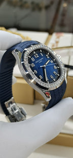 Patek Philippe watch angled view: blue dial, diamond bezel, blue rubber strap.