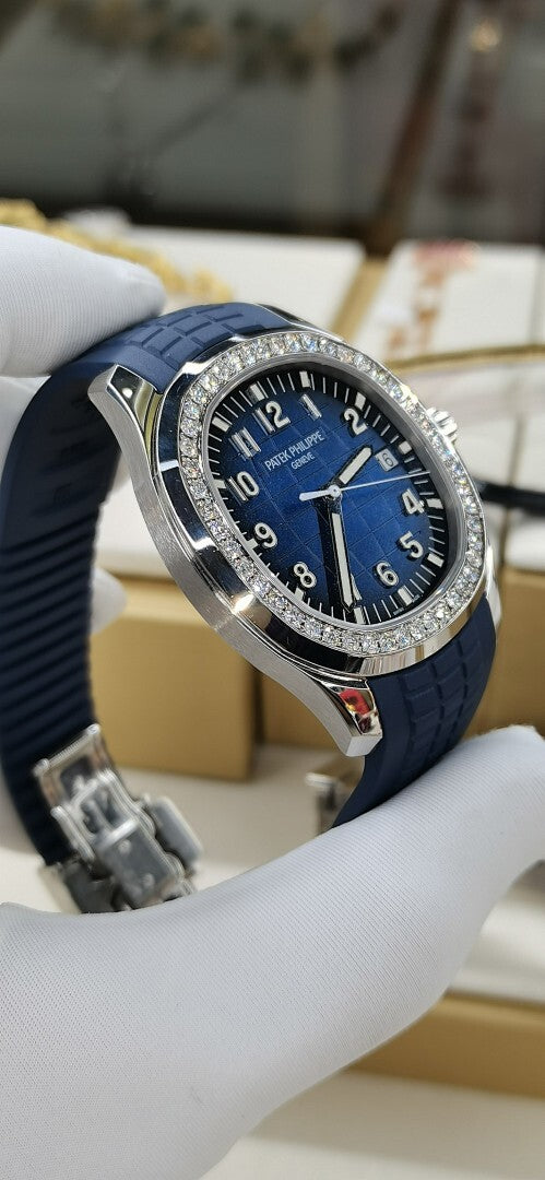 Patek Philippe watch angled view: blue dial, diamond bezel, blue rubber strap.