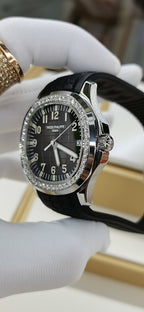 Patek Philippe wristwatch with black dial, diamond bezel, and black rubber strap