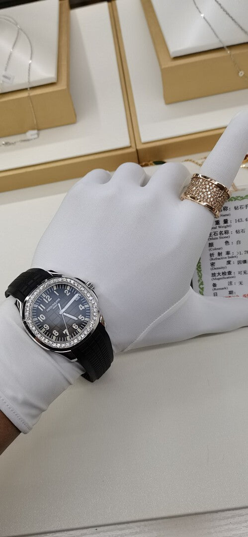 Patek Philippe wristwatch on white display cushion with black rubber strap