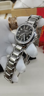 Luxury wristwatch with black dial, diamond-style bezel, and polished silver link bracelet