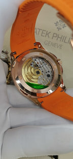 Patek Philippe watch with orange rubber strap, rose-gold caseback view of movement