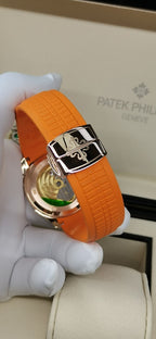 Patek Philippe watch with orange rubber strap and rose-gold clasp, visible dial window