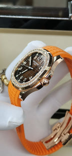 Patek Philippe watch with orange rubber strap, dark face, diamond bezel and crown