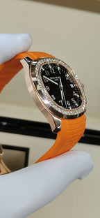 Patek Philippe watch with orange rubber strap, dark dial, sparkling diamond bezel, crown