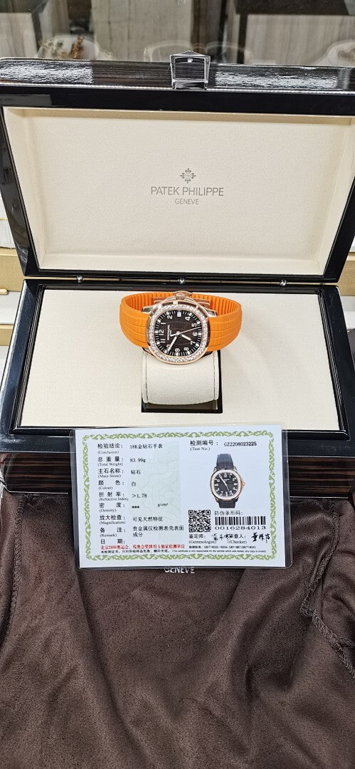 Patek Philippe watch in open box, orange rubber strap, dark dial, diamond bezel