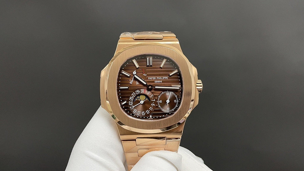 Patek Philippe watch on glove with dark brown dial and gold-tone bracelet