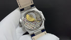 Patek Philippe watch back view, visible mechanical movement, blue leather strap.