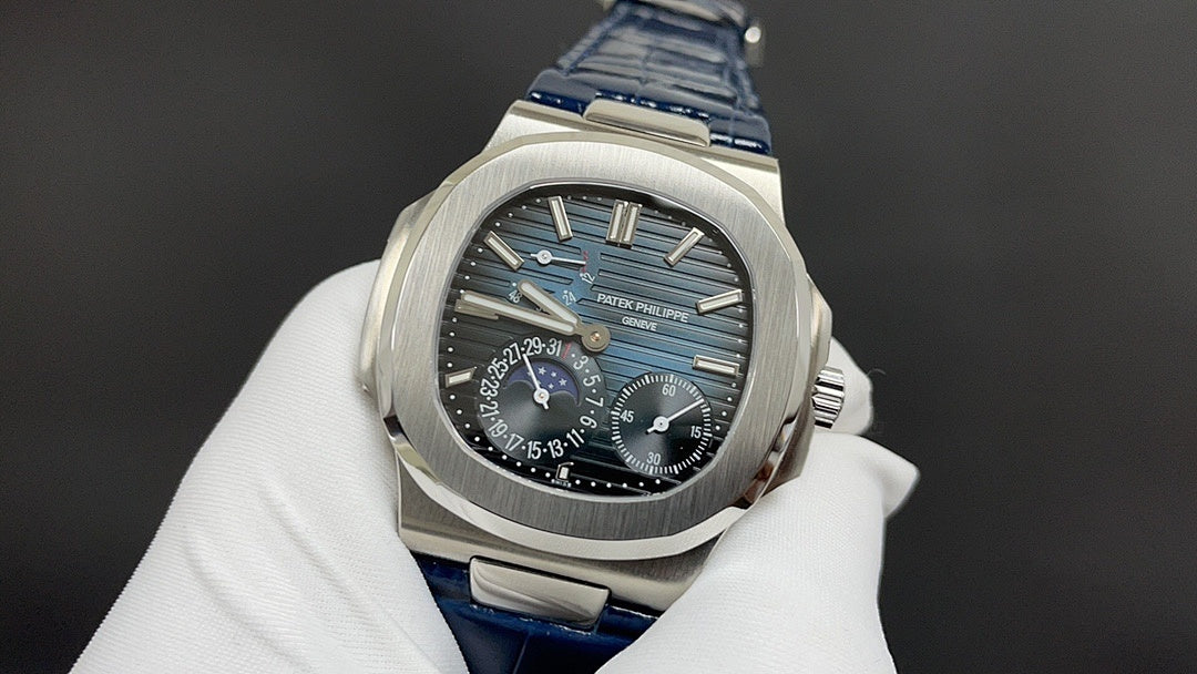 Patek Philippe watch front view, black dial with blue accents, blue leather strap.