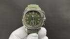 Green dial wristwatch with silver-tone case and green rubber bracelet, held by white gloves