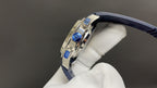 Patek Philippe wristwatch side view with crown and bezel accents, blue strap