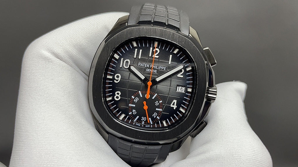 Patek Philippe wristwatch with black dial, orange center hand, and black rubber bracelet