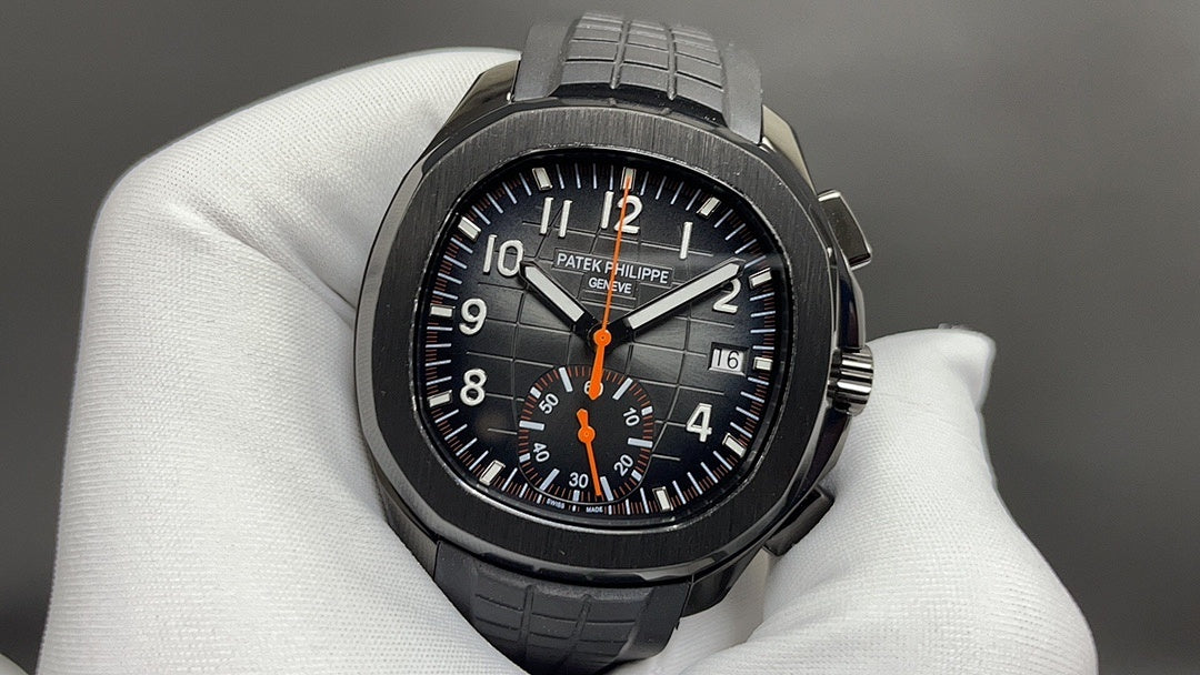 Patek Philippe wristwatch with black dial, orange center hand, and black rubber bracelet