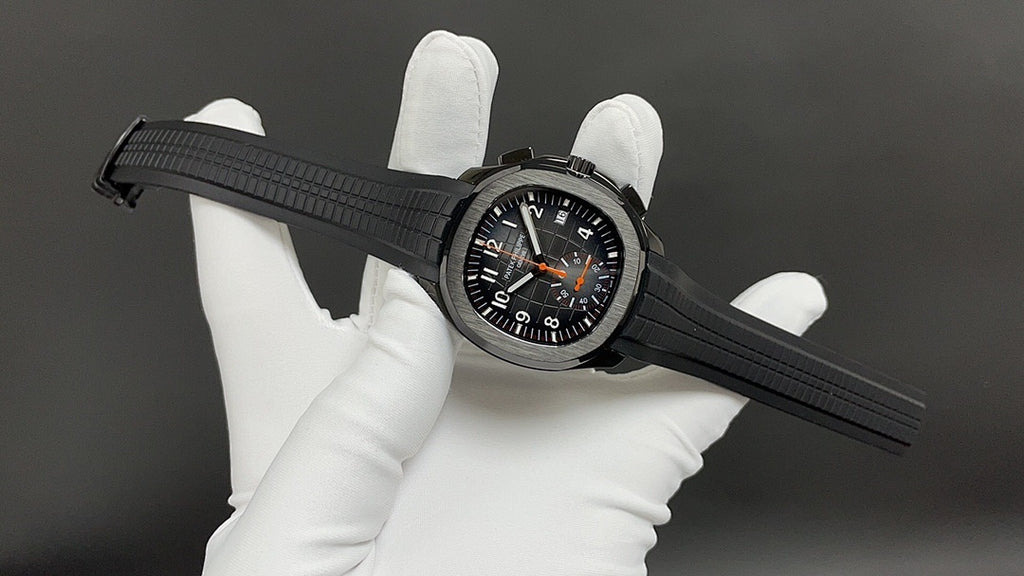 Patek Philippe wristwatch on black strap with black dial and orange accents