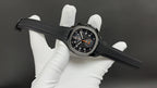 Patek Philippe wristwatch on black strap with black dial and orange accents