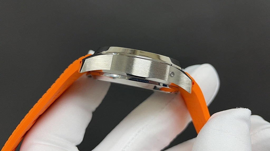 Patek Philippe wristwatch side close-up with orange strap and polished stainless case.