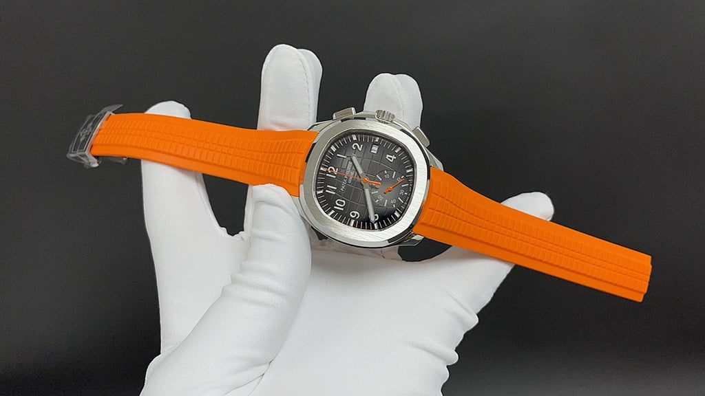 Patek Philippe wristwatch on orange strap with black dial and silver case, angled view.