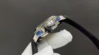 Patek Philippe watch side with crown and blue accents, black strap, stainless case
