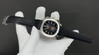 Patek Philippe watch on black strap with black dial, orange hands, steel case