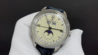 Patek Philippe wristwatch with cream dial, blue leather strap, subdials and Roman numerals.