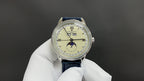 Patek Philippe wristwatch front view, white dial, textured blue leather strap.
