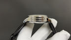 Wristwatch case close-up with polished stainless steel bezel and black leather strap