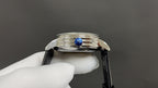 Wristwatch crown and blue gemstone detail on polished stainless steel case with black leather strap