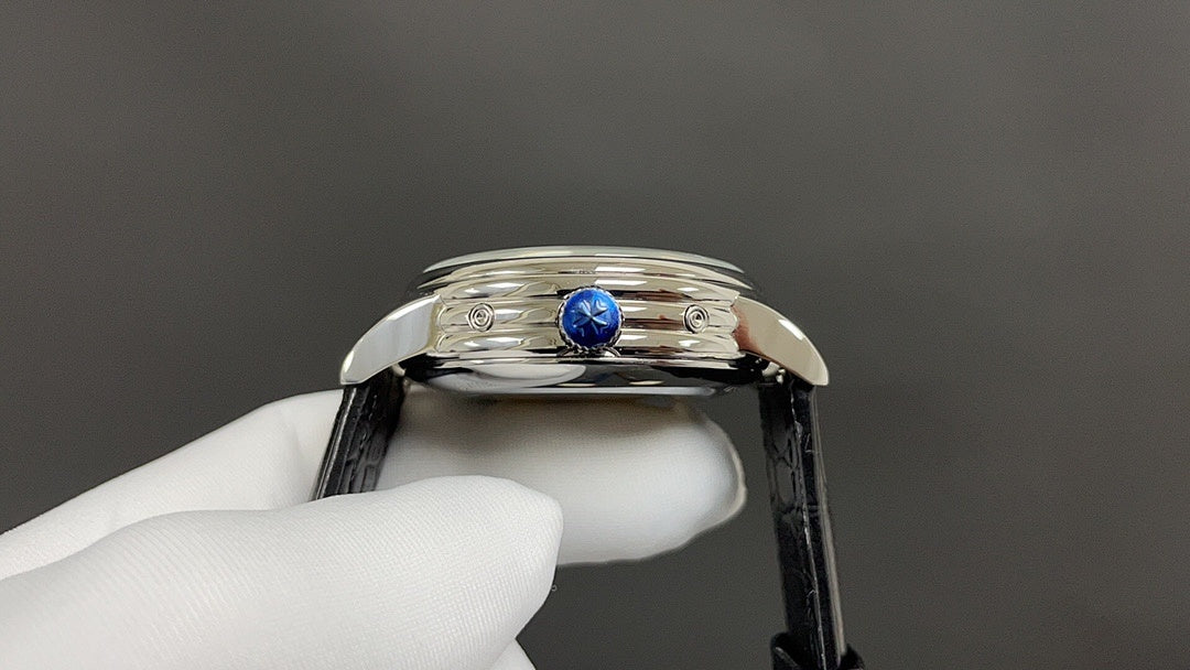 Wristwatch crown and blue gemstone detail on polished stainless steel case with black leather strap