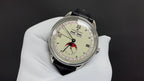 Stainless steel wristwatch with cream dial, red bird motif, and black leather strap