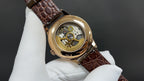 Luxury wristwatch back with gold-tone case and brown leather strap, openwork movement
