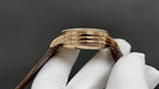 Luxury wristwatch case back, gold-tone finish with brown leather strap
