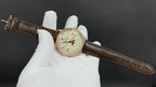 Luxury wristwatch on brown leather strap with round white dial and gold-tone case
