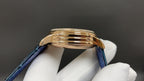 Patek Philippe watch with blue leather strap and gold-tone case, side profile.