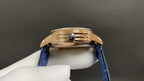 Patek Philippe watch with blue leather strap and gold-tone case, crown side detail.