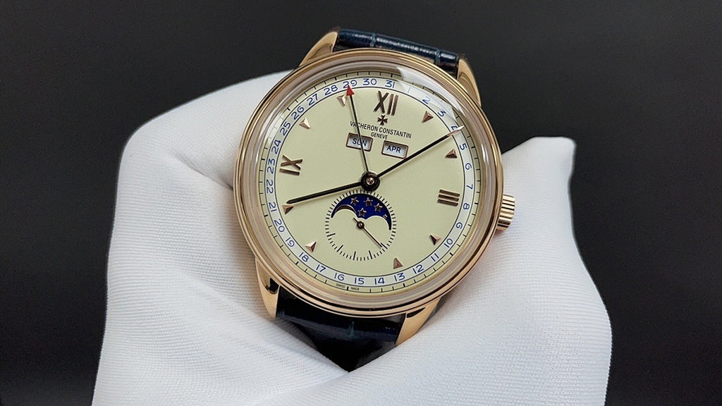 Patek Philippe watch with blue leather strap and gold-tone case, cream dial with roman numerals.