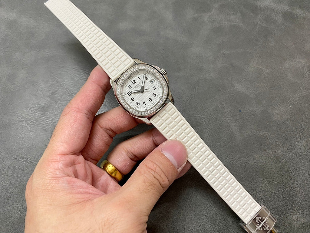 Diamond bezel wristwatch with white dial, textured white strap, and metal buckle