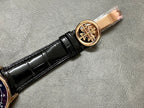 Patek Philippe wristwatch crown with gold emblem, black leather strap