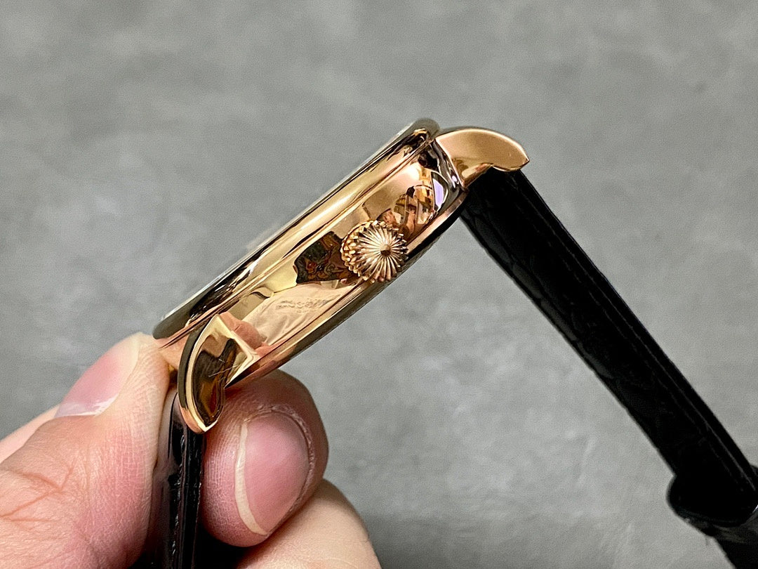 Patek Philippe wristwatch case side with gold crown and emblem, black leather strap