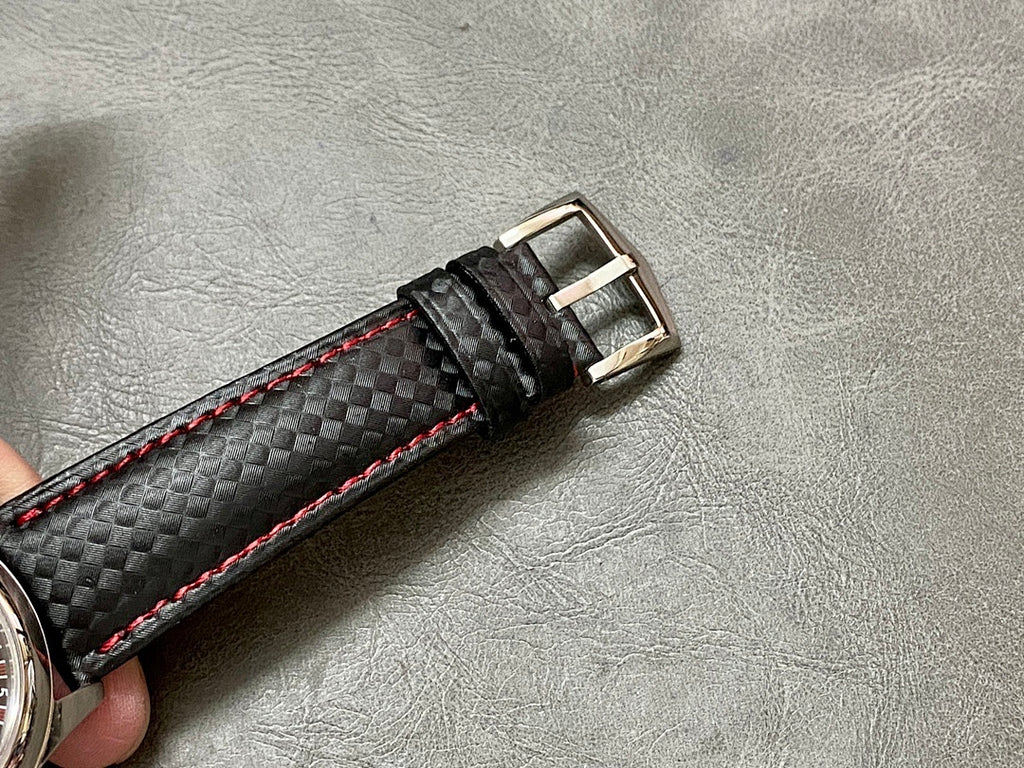 Black leather watch strap with red edge stitching and metal buckle