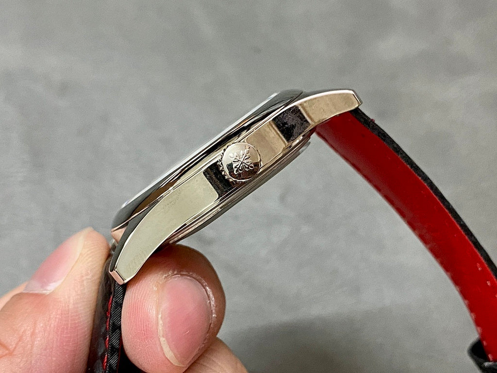 Stainless watch case top with crown and engraved back, on red leather strap