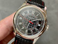 Round stainless watch with dark dial, red accents, and black patterned leather strap